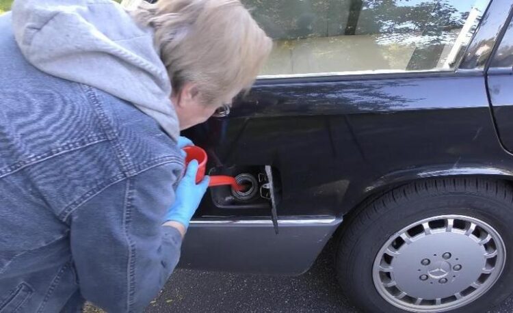 A person pouring cleaner into a fuel tank